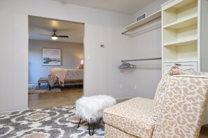 A bedroom with a bed, a white fluffy chair, a leopard print ottoman, a ceiling fan, a painting, and a white wardrobe. - Tierra Velo - HGTV Style in East Tucson (Tucson)