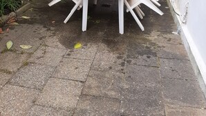 Pieni ulkotila, jossa on pyöreä pöytä ja neljä tuolia. Tilaa ympäröi matala tiiliseinä ja siellä kasvaa puu.