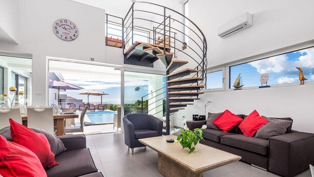 Un salon moderne avec un escalier en colimaçon, une vue sur la piscine et un coin salon confortable.