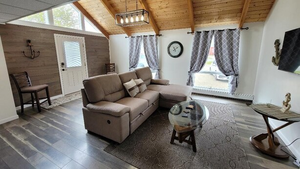 A living room with a sectional sofa, a glass coffee table, and a wooden ceiling. - Perfectly centered in the Birch Harbor Village! (Birch Harbor)