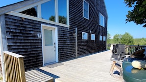 A modern house with a wooden deck, a large window, and a small garden area. - Perfectly centered in the Birch Harbor Village! (Birch Harbor)
