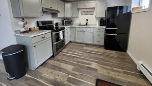 A kitchen with white cabinets, a black refrigerator, a microwave, and a gas stove. - Perfectly centered in the Birch Harbor Village! (Birch Harbor)