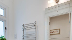 A modern bathroom with a white toilet, a glass shower enclosure, and a white sink with a mirror above it.
