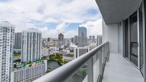 En høj bygning med balkon med udsigt over bybilledet, inklusive en flod og forskellige andre bygninger.