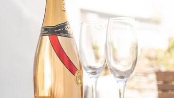 A bottle of Acker champagne and two empty glasses on a wooden table.
