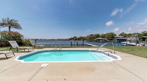 A rectangular swimming pool with a tiled edge, surrounded by a concrete deck.
