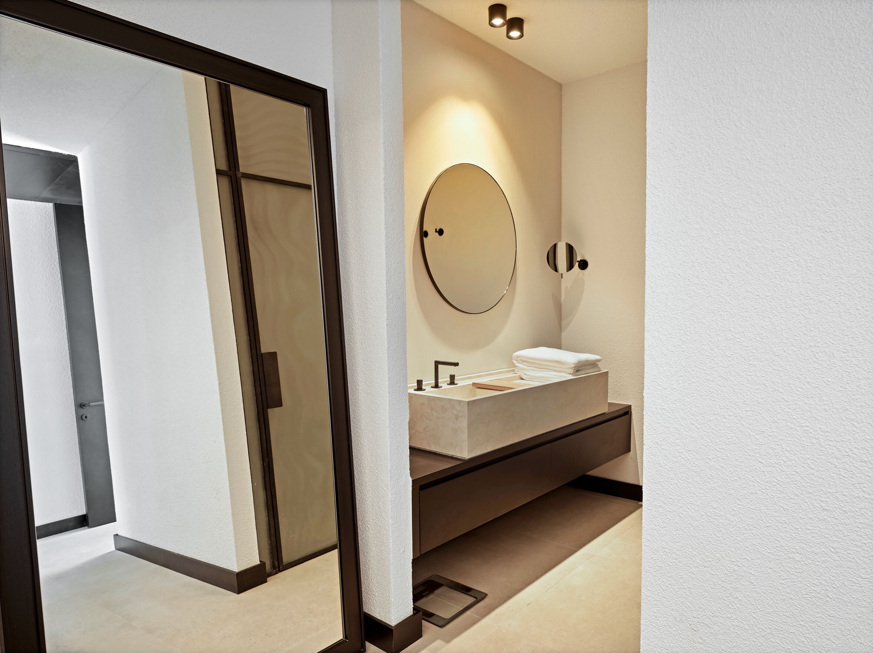 Un baño moderno con un espejo grande, un lavabo y un perchero para toallas.
