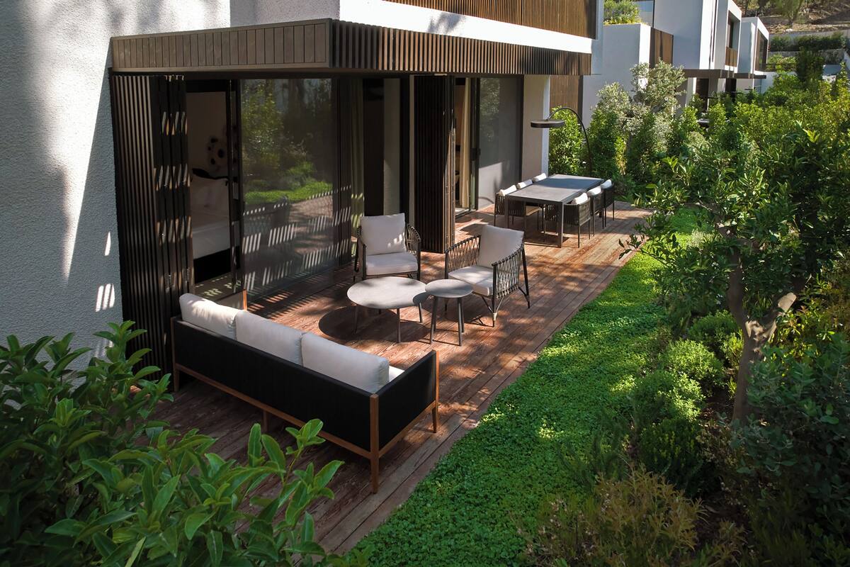 Une terrasse extérieure avec un canapé, des fauteuils et une table.