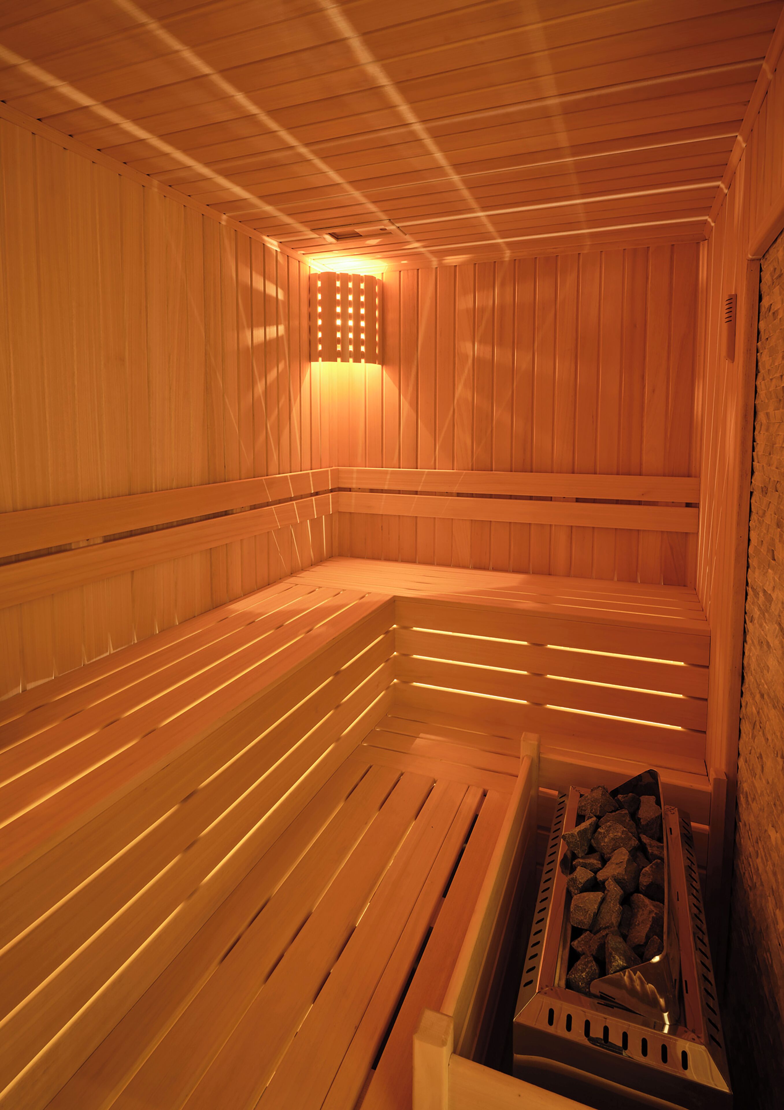 A sauna with wooden benches and a stone wall.