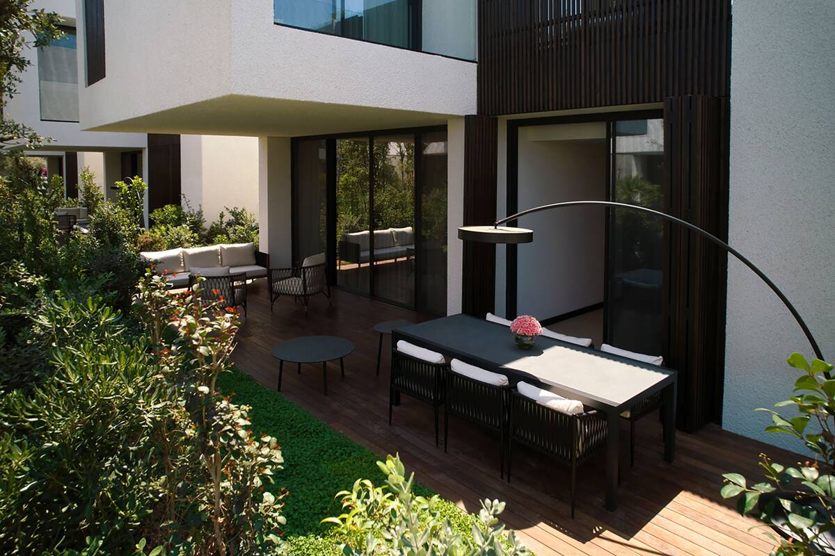 Une terrasse extérieure aménagée avec un ensemble de mobilier de jardin, un canapé et une lampe.