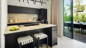 Cocina moderna con una isla central, armarios negros y un amplio ventanal con vistas a zonas verdes.