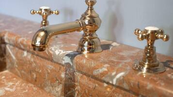 A marble sink with three gold faucets.