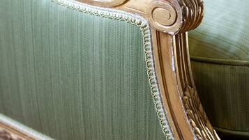 Primer plano de una silla tapizada en verde con elaboradas tallas de madera y un respaldo decorativo.