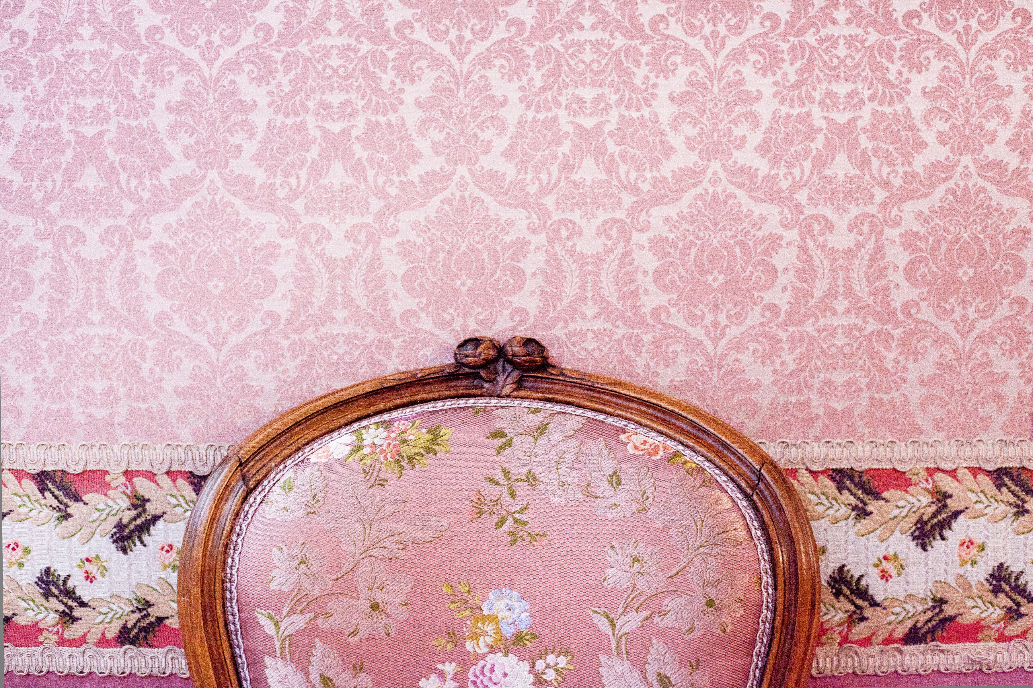 A vintage-style chair with a floral embroidered fabric and a wooden frame.