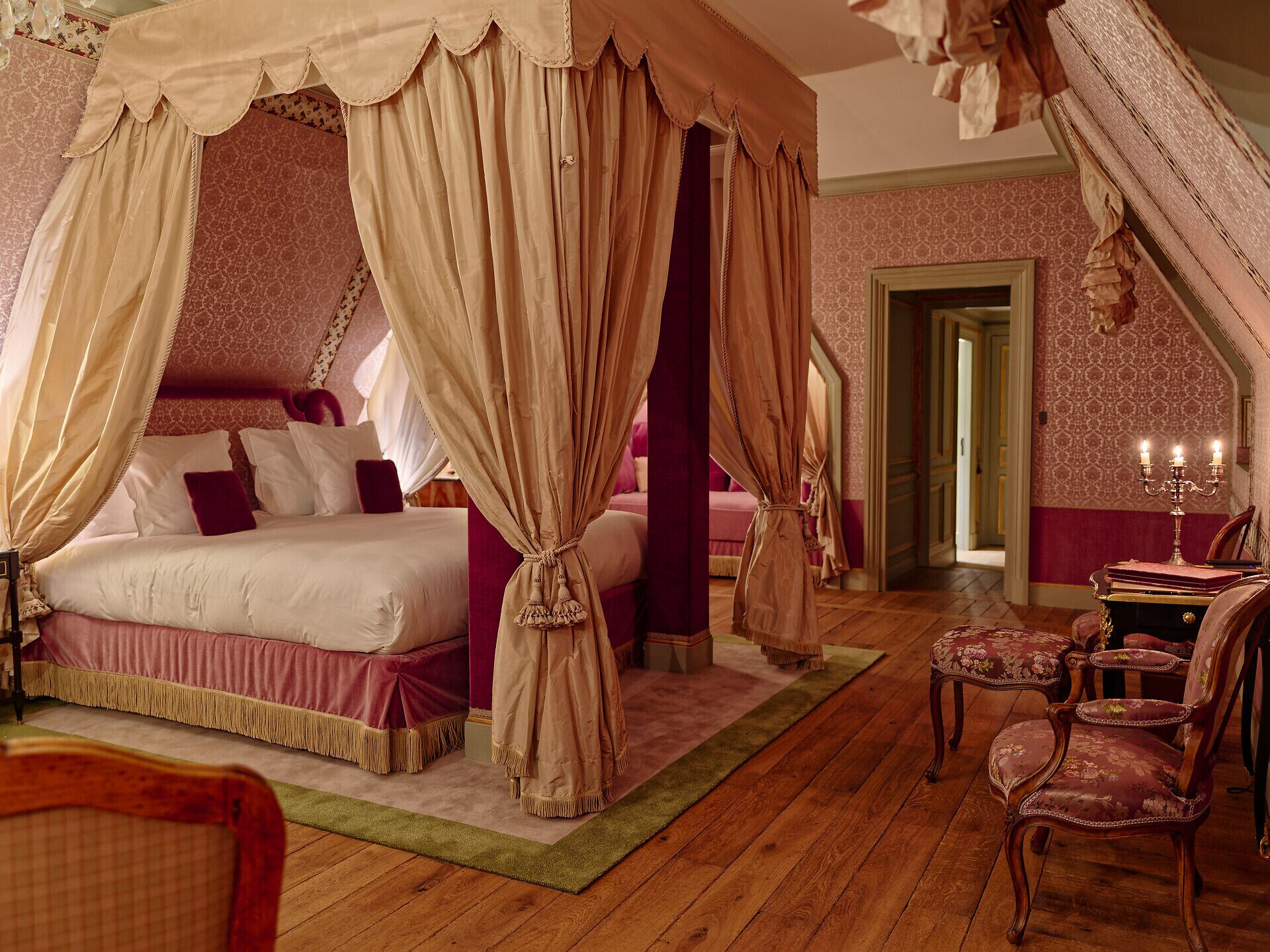 A bedroom with a four-poster bed, a canopy, and a wooden floor.