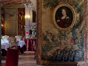 A room with ornate decor, including a tapestry, a framed portrait, and a chandelier. - Château Louise de La Vallière (Reugny)