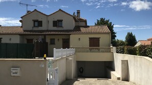 Un bâtiment à deux étages, doté d’un toit recouvert de tuiles et d’une terrasse sur le toit à surface plane.
