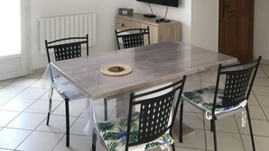 Un coin repas avec une table en bois, quatre chaises, un téléviseur et un radiateur.