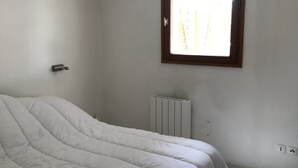 Une chambre à coucher avec un lit, une fenêtre, un radiateur et un luminaire.