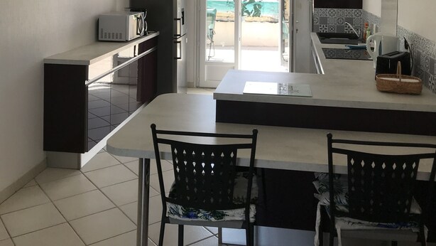Une cuisine moderne avec un coin repas, une vue sur la plage à travers la porte-fenêtre coulissante et un petit balcon.