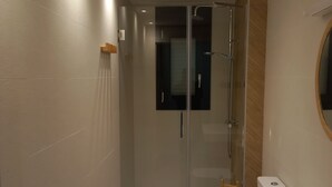 Ein modernes Badezimmer mit Duschkabine aus Glas, Toilette und Waschbecken mit Spiegel.