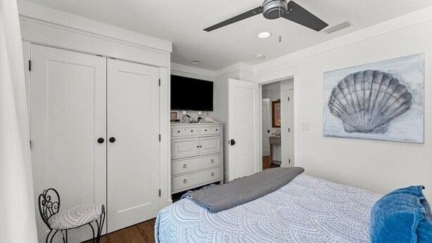 A bedroom with a bed, a chair, a dresser, a ceiling fan, and a painting on the wall. - Waterfront Sunsets~ Private Dock ~ Heated pool! (Panama City)