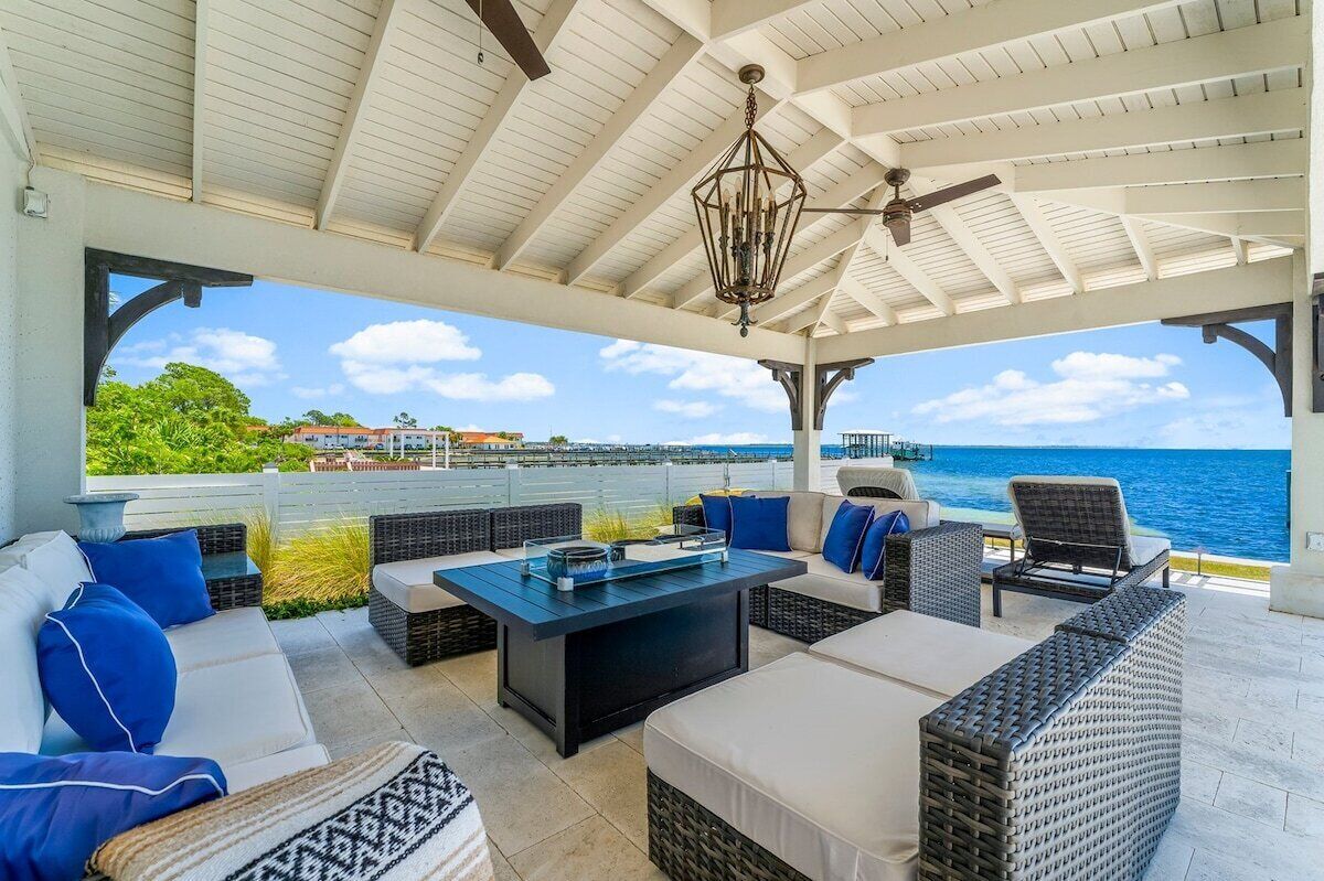 An outdoor patio with wicker furniture, a table, and a view of the ocean.