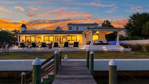 A waterfront property with a covered patio, outdoor seating, and a wooden dock leading to the house. - Waterfront Sunsets~ Private Dock ~ Heated pool! (Panama City)