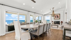 Une salle à manger spacieuse avec vue sur la mer, un lustre et une cheminée.