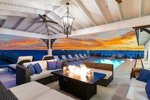 Eine Dachterrasse mit Sitzgelegenheiten im Freien, einem Pool und Blick auf den Sonnenuntergang.