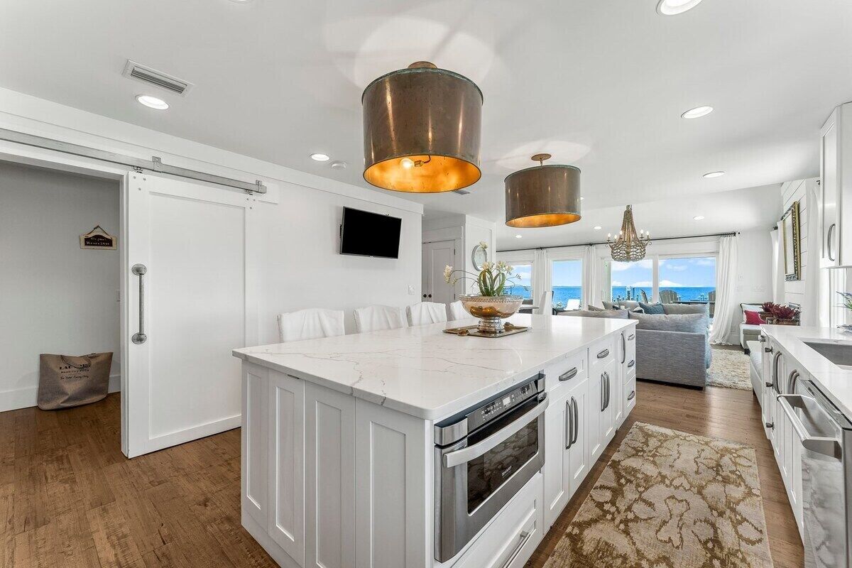 A modern kitchen with a large island, stainless steel appliances, and pendant lighting.