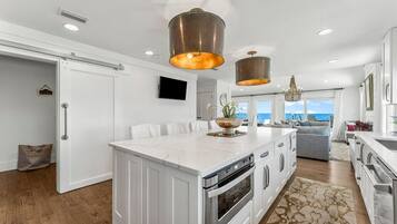 A modern kitchen with a large island, stainless steel appliances, and pendant lighting.