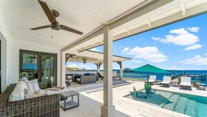 A covered outdoor area with a pool, lounge chairs, and a view of the ocean. - Waterfront Sunsets~ Private Dock ~ Heated pool! (Panama City)