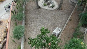 Ein Garten mit einer runden Steinstruktur, Kiesboden und einem weißen Zaun.