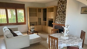 Ein Wohnzimmer mit einer Couch, einem Esstisch mit Stühlen, einem Kamin und eingebauten Regalen.