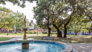 Ein Springbrunnen in einem Park mit einer Bank und Bäumen.