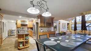 A spacious kitchen with wooden cabinets, a dining area with a large table, and a cozy seating area with a sofa and a piano. - Paradise Pocono - Ultimate Arcade, Salt Pool and Hot Tub - Sleeps 14 (Cresco)