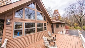 A cabin with a large deck, multiple windows, and a stone exterior. - Paradise Pocono - Ultimate Arcade, Salt Pool and Hot Tub - Sleeps 14 (Cresco)