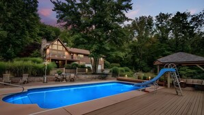A swimming pool with a blue slide, deck chairs, and a gazebo. - Paradise Pocono - Ultimate Arcade, Salt Pool and Hot Tub - Sleeps 14 (Cresco)