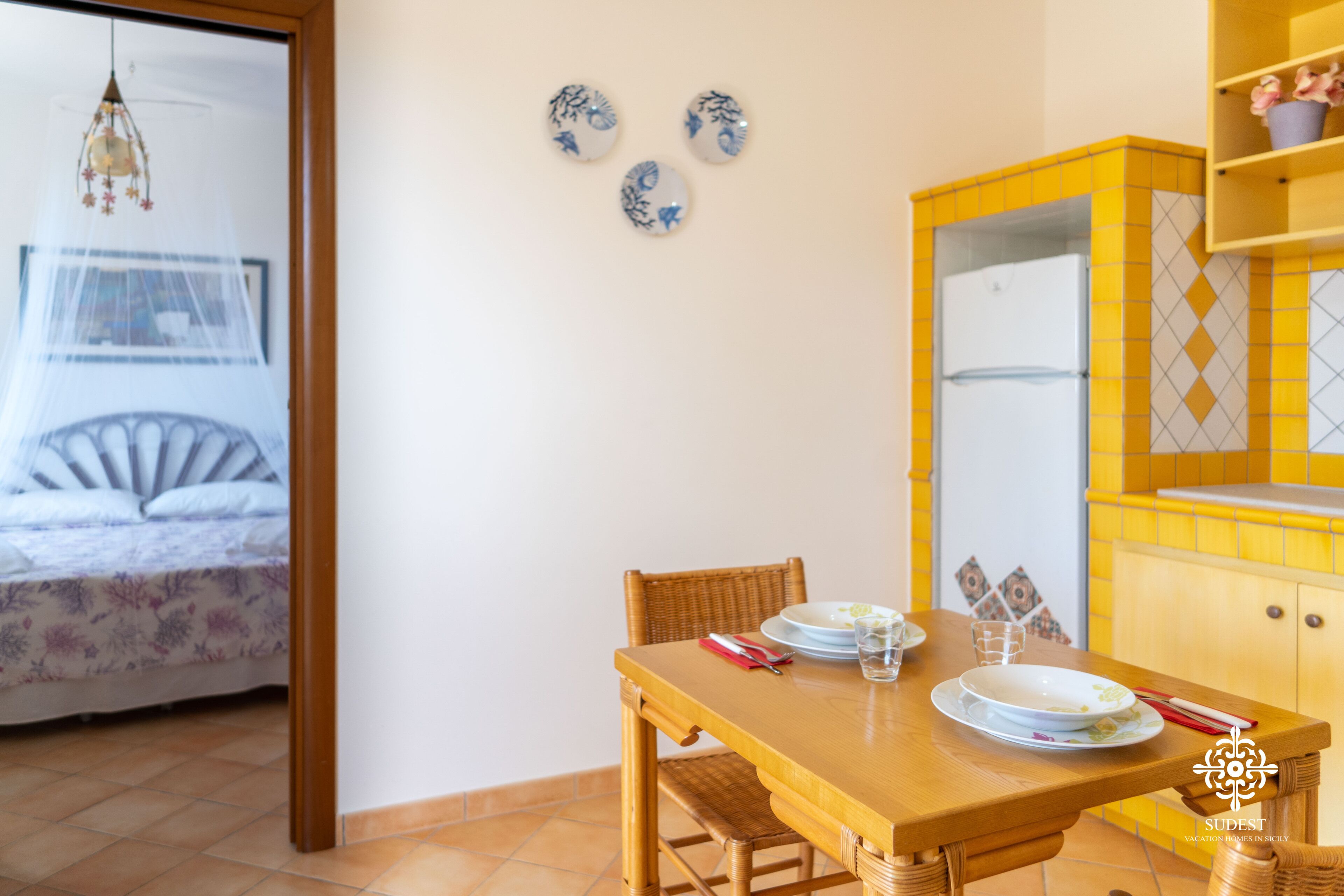 A dining area with a wooden table, chairs, and a yellow cabinet with a mirror.