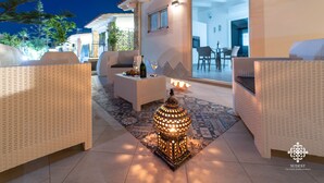 Un patio al aire libre con mobiliario de mimbre, un farol decorativo y piso de baldosas.
