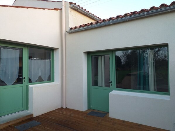 A small, single-story building with two green-framed windows and a white exterior. - Between bocage sea and marais poitevin (Thiré)