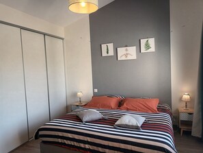 A bedroom with a bed, striped bedding, and three wall-mounted pictures. - Between bocage sea and marais poitevin (Thiré)