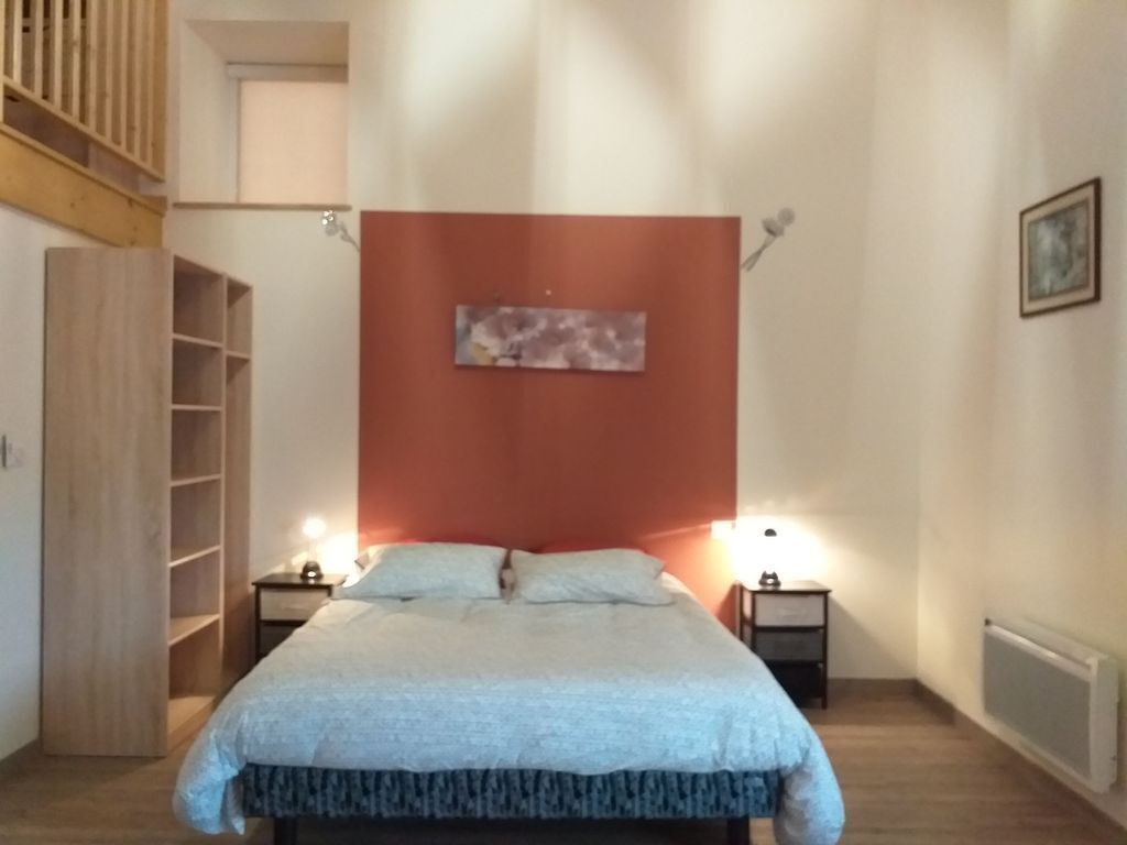Une chambre à coucher comprenant un lit, deux tables de chevet, une commode, une armoire et un tableau accroché au mur.