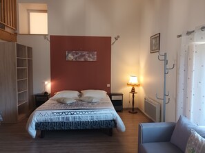 A bedroom with a bed, bedside tables, a lamp, a chair, and a wall-mounted coat rack. - Between bocage sea and marais poitevin (Thiré)