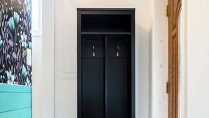 A hallway with a black wardrobe, a wooden door, and a teal-colored wall. - Tiny House Apt in Little Italy w OffStreet Parking (Wilmington)