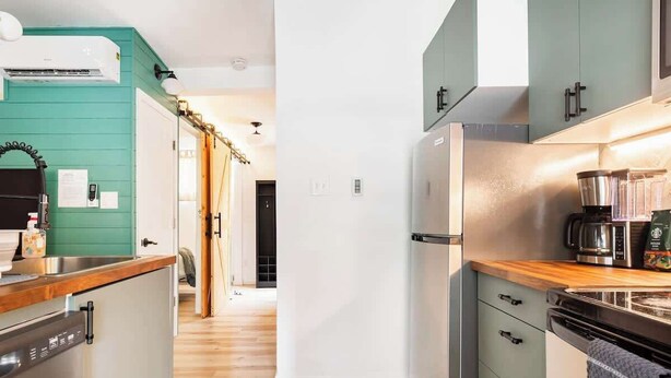 A compact kitchen with a dishwasher, a coffee maker, and a refrigerator. - Tiny House Apt in Little Italy w OffStreet Parking (Wilmington)