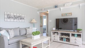 A living room with a grey sofa, a coffee table, a TV, and a wooden sideboard with drawers.