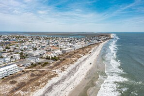 Vista aérea de una zona residencial costera con casas a lo largo de la playa, cielo despejado y mar tranquilo.