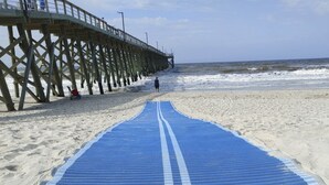 A beach with a blue mat leading to a wooden pier. - *Beach House!!*Views!!*Steps to Ocean!*Amenities! (Oak Island)